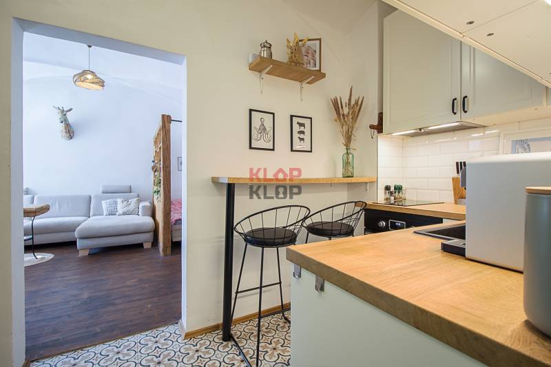 A kitchen in a studio apartment with a bar counter, armchairs, and wall decorations.