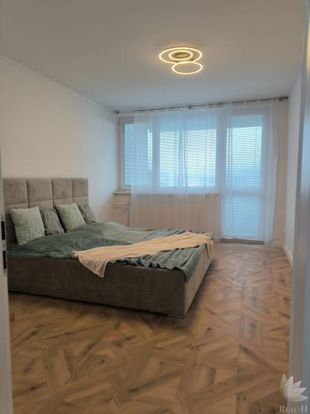 Bedroom in a 4-room apartment with a bed and a wooden decor floor.