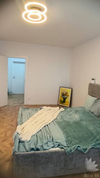 Bedroom with a light fixture and a bed, floor with wood decor, 4-room apartment.
