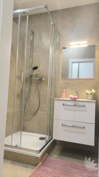 Bathroom with a shower, sink on a cabinet, mirror, and mirror lighting in a 4-room apartment.