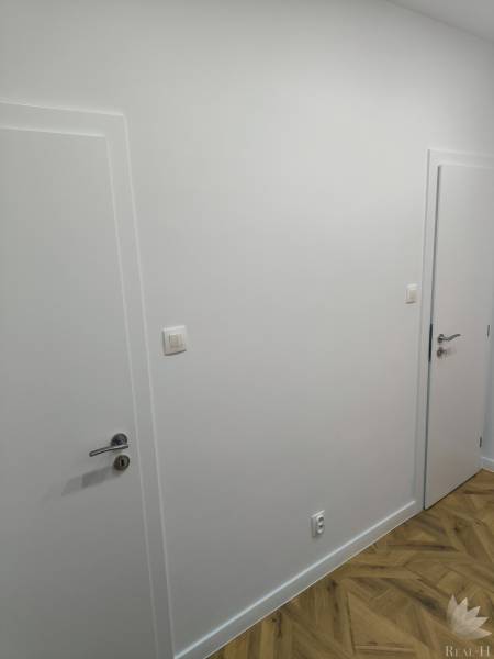 White walls with doors and a wooden decor floor in a 4-room apartment.