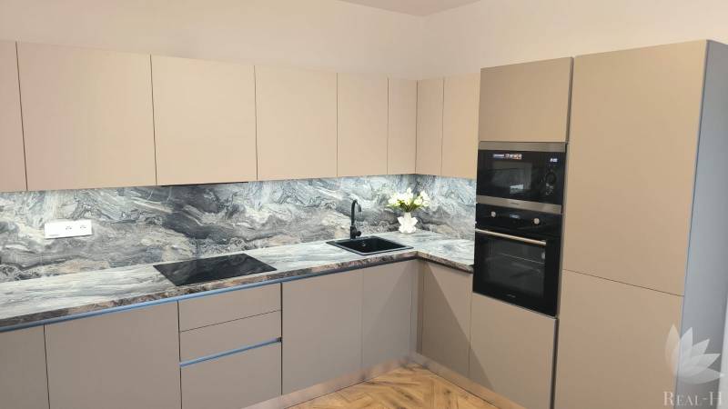 Kitchen in a 4-room apartment with a kitchen unit, appliances, and flooring with a wood decor.