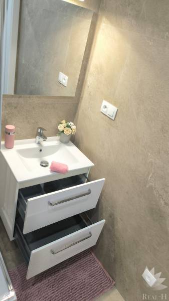 Bathroom with a mirror, sink, open drawers, and decorative roses in a 4-room apartment.