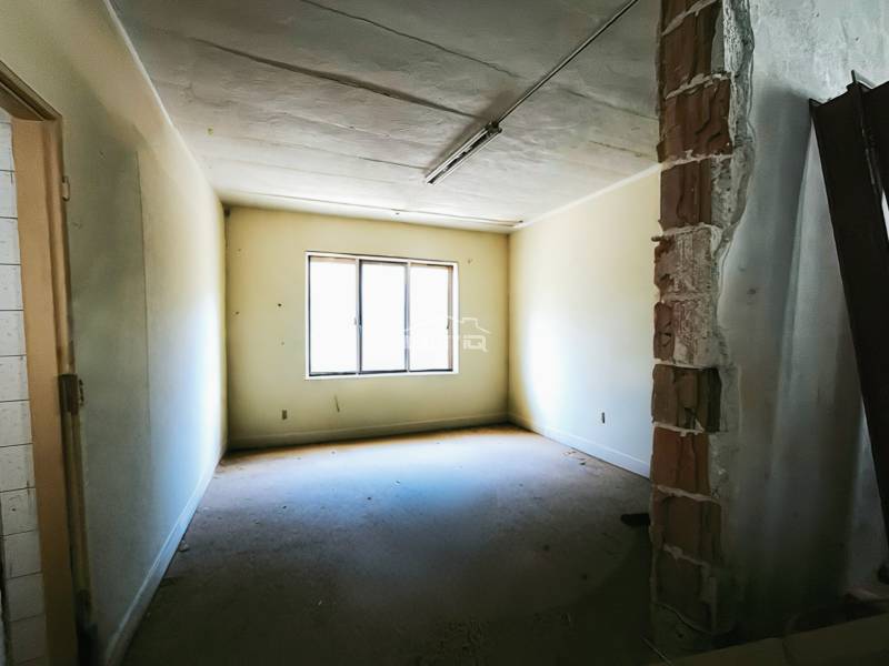 A room in a production area with a window, yellow walls, and an exposed brick section of the wall.