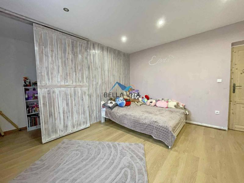 A room with sliding doors, a wooden decor floor, and a bed in a family house.