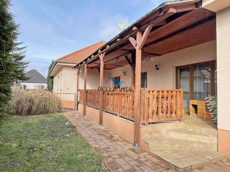 A family house on Hodská in Galanta with a terrace and garden, surrounded by greenery and paving.