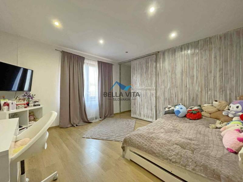 Children's room in a family house with a wooden decor floor and toys on the bed.