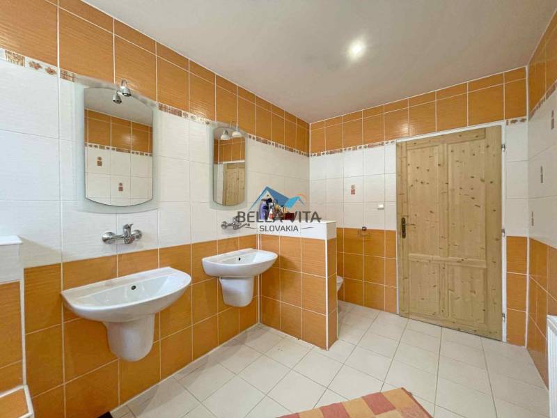 A bathroom in a family house with orange and white tiles, a double sink, and mirrors.