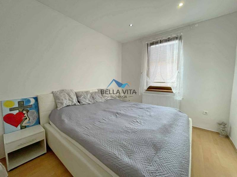 Bedroom in a family house with a bed, a painting, and a wooden decor floor.