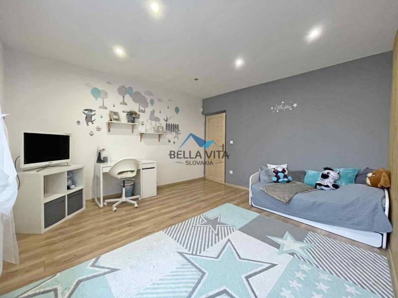 Interior of a family house with a writing desk, television, and wooden decor flooring.