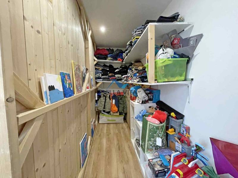 Narrow storage spaces in a family house with shelves full of clothes and toys.