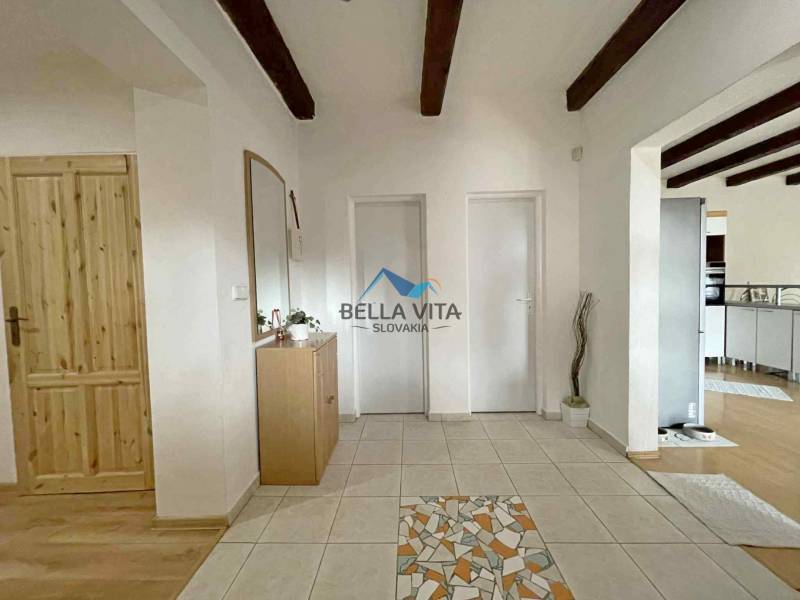 Interior of a family house with ceramic tiles and wooden decor flooring, visible beams.