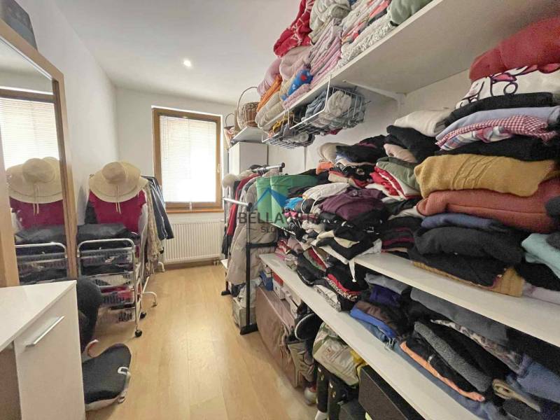 A wardrobe in a family house with a wooden decor floor and shelves for clothes.