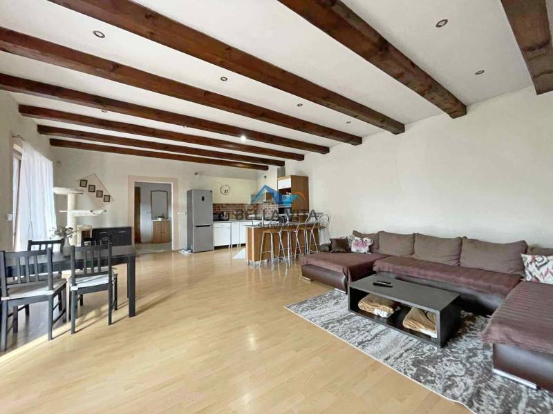 Living room of a family house with a wood-patterned floor, a large sofa, and a dining table.