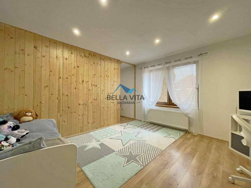 Children's room with a wooden wall, wooden decor flooring, and a decorative carpet.