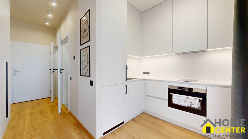 Kitchen corner with built-in appliances in a studio apartment, floor with wood decor.