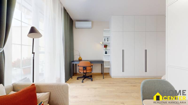 Spacious work corner in a studio apartment with a wood-patterned floor and a large window.