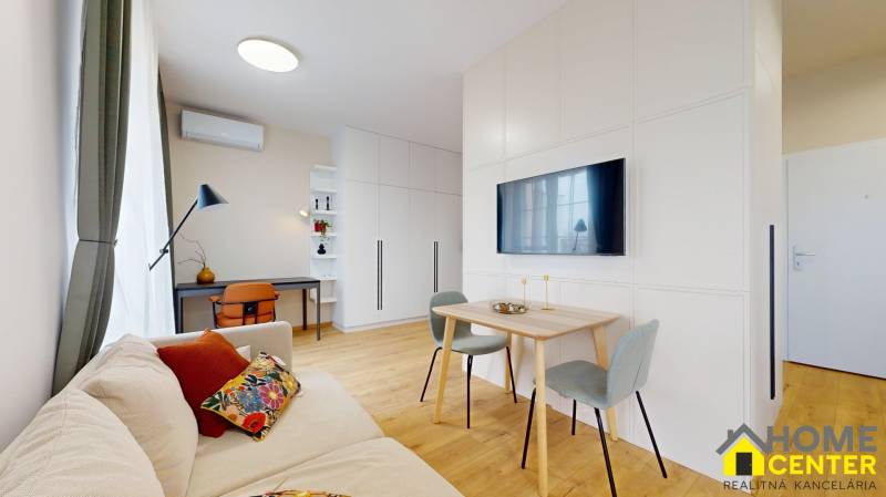 Living room in a one-bedroom apartment with wood-patterned flooring and a desk.