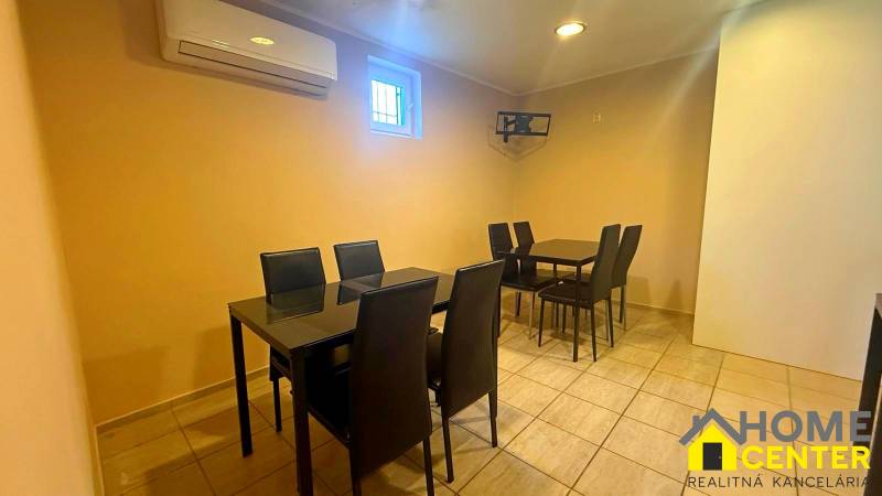 Interior of a gastro space with black chairs and tables on light tiles.