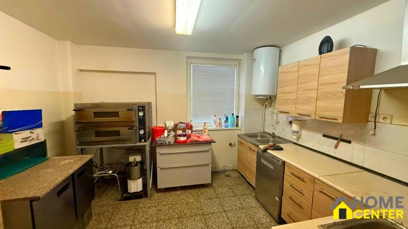 Kitchen gastro spaces with an oven, cabinets, and a sink on a stone floor.