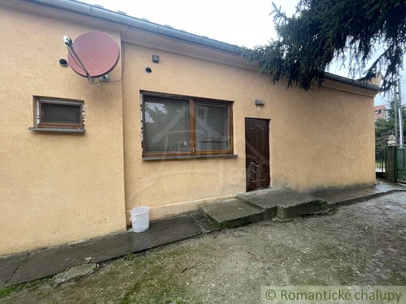 A family house in Neded with a beige facade, satellite, and wooden windows.