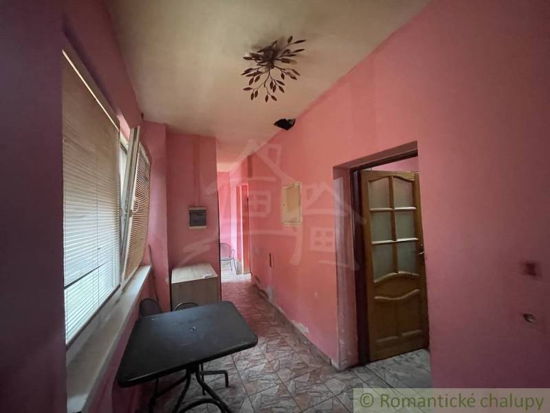 Interior of a family house with pink walls, tiled floor, and a table.