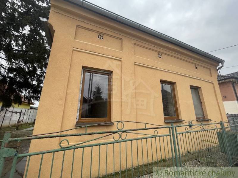 A family house in Neded with a striking yellow facade and a colorful fence.