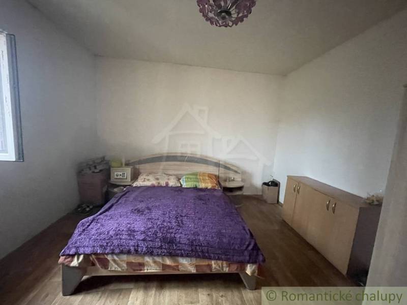 Bedroom in a family house with a bed, cabinet, and floor with a wooden decor.