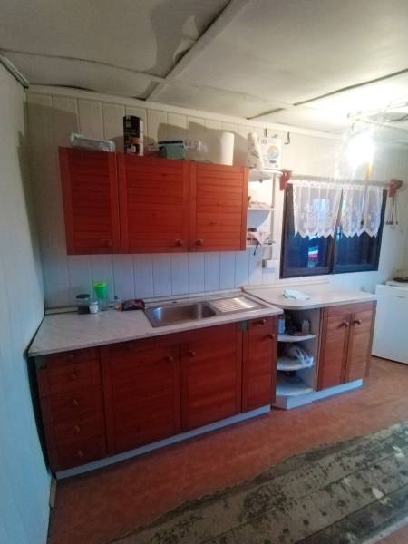 A kitchen unit with wooden cabinets, a sink, and a curtain in the interior of the garden.