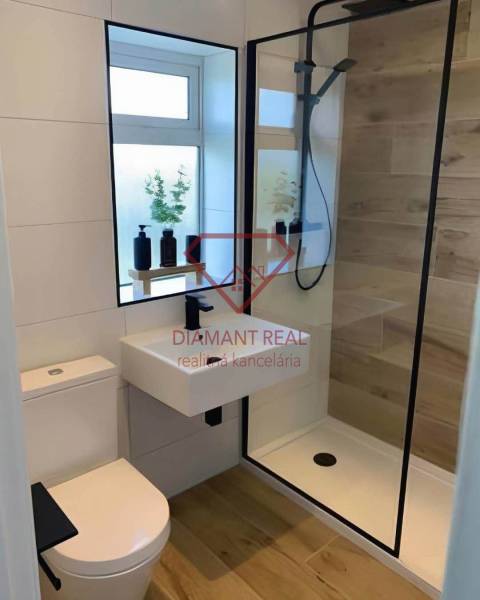 Bathroom in a 3-room apartment with a glass shower enclosure and a floor with a wooden decor.