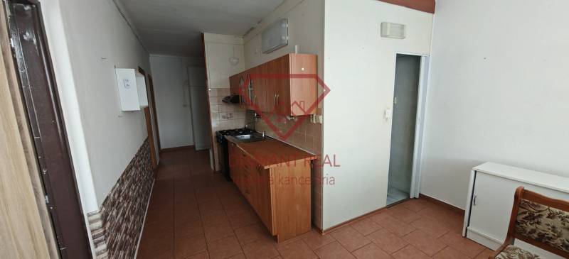 A narrow kitchen in a 3-room apartment with tiled flooring and wooden cabinets.