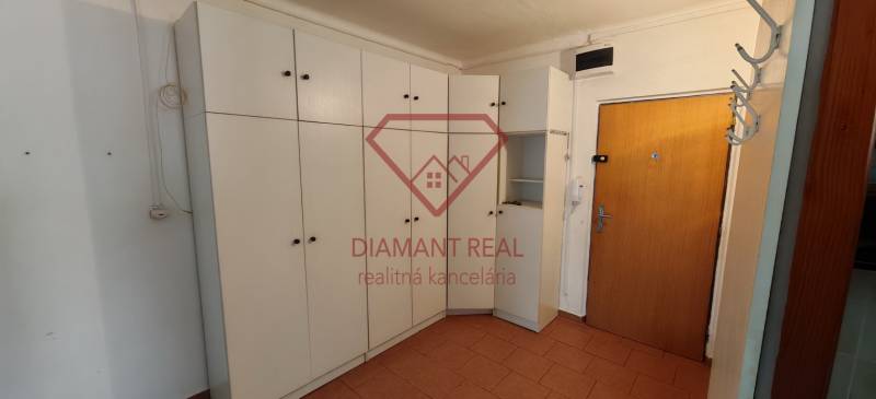 A hallway of a 3-room apartment with a white wardrobe and brown doors.