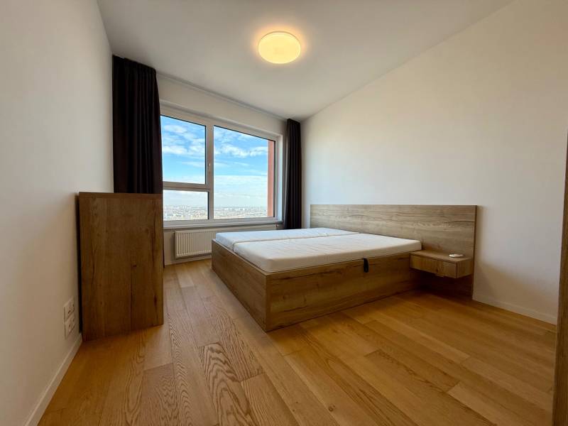 A bedroom with wood-patterned flooring and a view in a 3-room apartment.