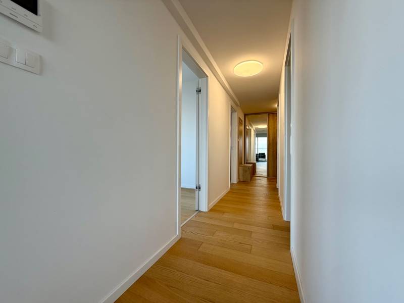 A hallway in a 3-room apartment with a wooden decor floor and light-colored walls.