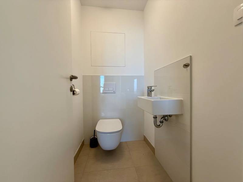 Bathroom with toilet and sink in a 3-room apartment, light tiles and flooring.