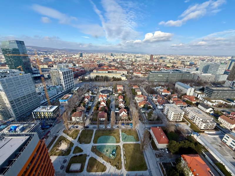 A view of the Bratislava skyline with contemporary architecture, greenery, and sports facilities.