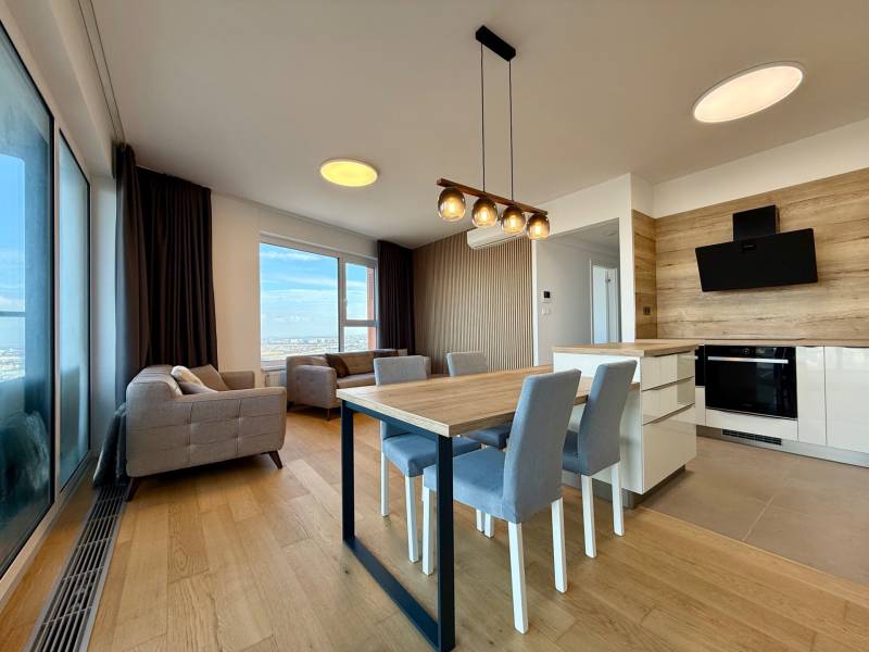 Living room with a kitchenette, equipped with sofas, a dining table, and a floor with a wooden decor.