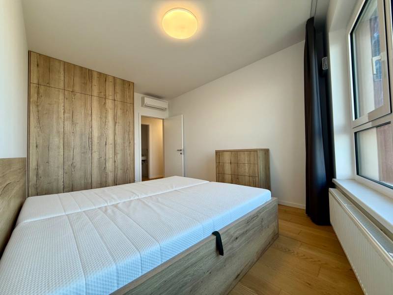 A bedroom in a 3-room apartment with a wood-decor floor, a built-in wardrobe, and a large window.