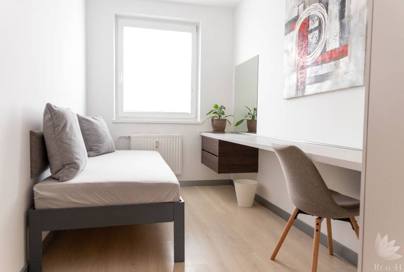 A room in a 4-room apartment with a bed, a table, and a floor with a wooden decor.