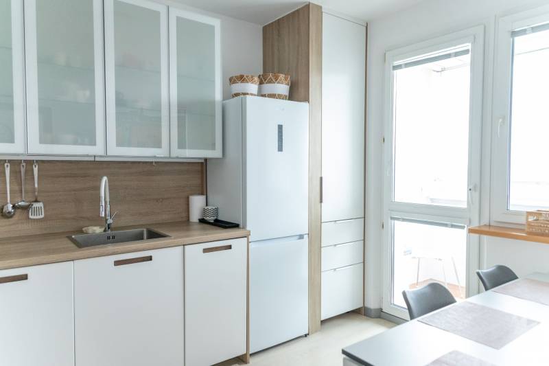 Spacious kitchen in a 4-room apartment with white cabinets and a large window.