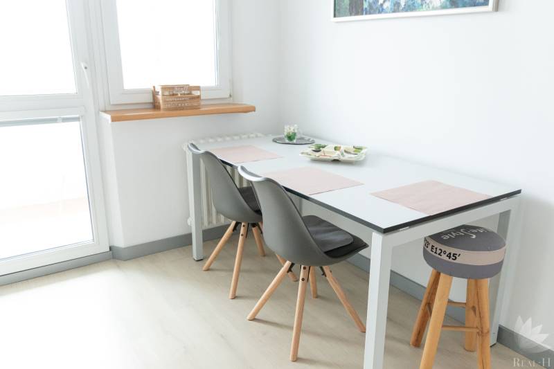 Dining area with a table and chairs in a 4-room apartment, floor with a wooden decor.