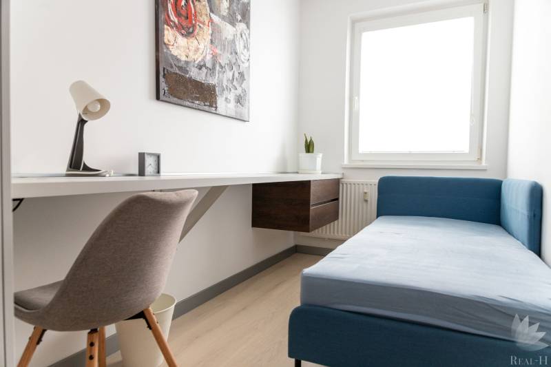 A workspace in a 4-room apartment with a sofa and a table on a light floor.