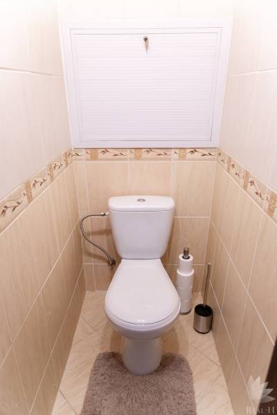 A toilet with beige tiles and carpet in a 4-room apartment.