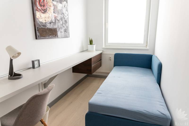A small room in a 4-room apartment with a blue sofa and a wooden decor floor.
