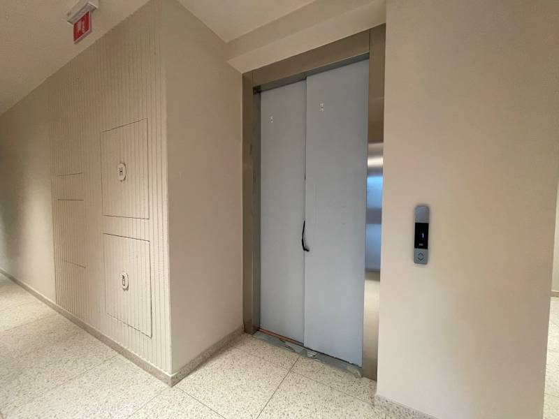 Shared hallway with an elevator in an apartment building, neutral walls and light flooring.