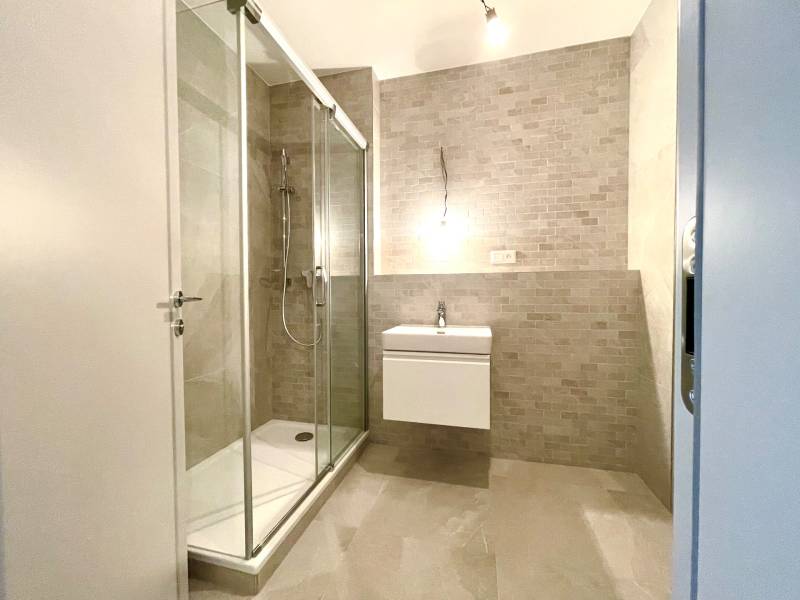 Bathroom in a 2-room apartment with a shower and a simple sink.