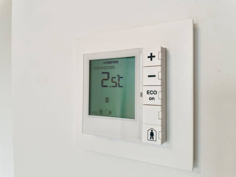 Wall thermostat with display in a 2-room apartment for temperature regulation.