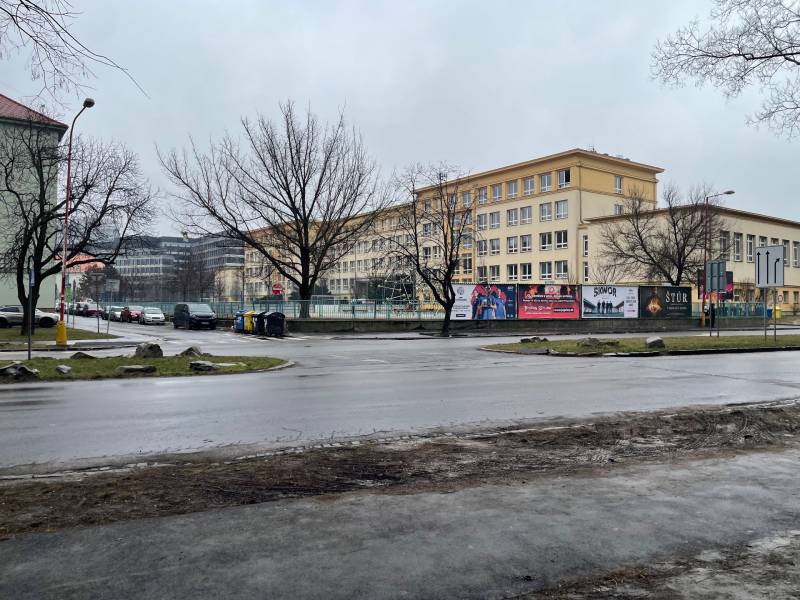 A city street in Košice with buildings, trees, and a road in rainy weather.