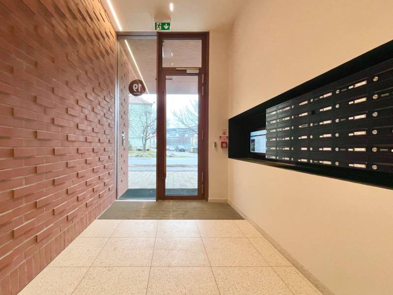 Entrance to the apartment building with mailboxes and a brick wall on Košická in Bratislava.