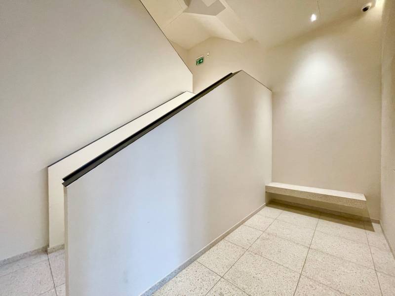 A staircase with white walls, a railing, and a stone floor in a residential building.